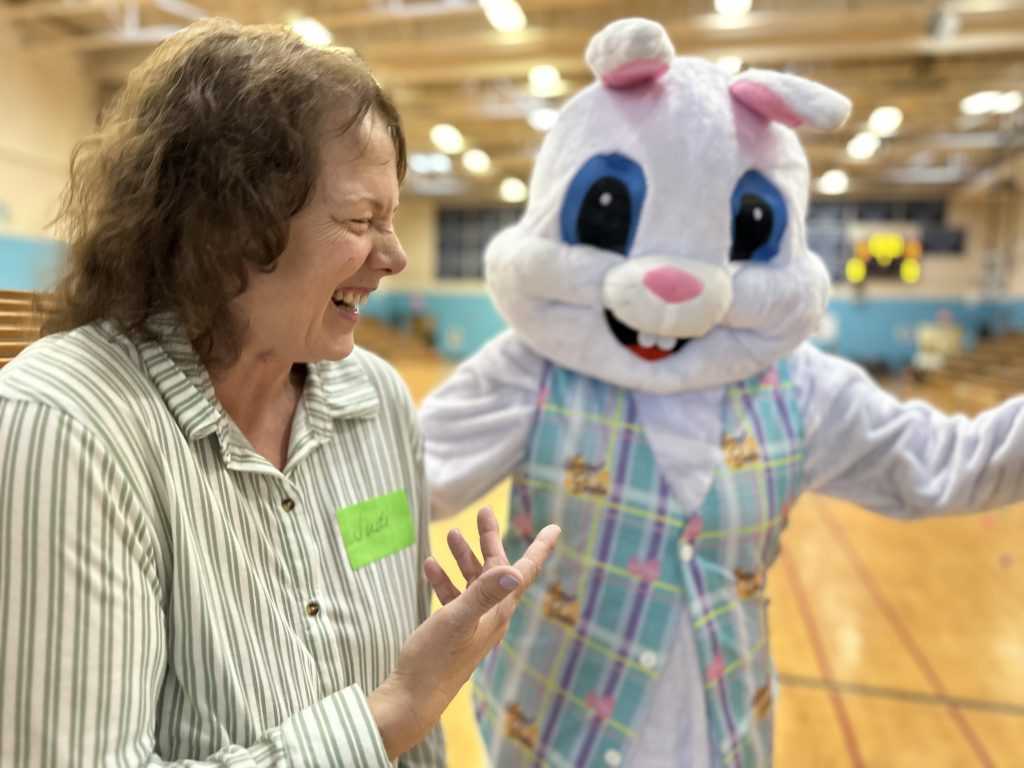 A woman laughs as the Easter Bunny looks at the camera.