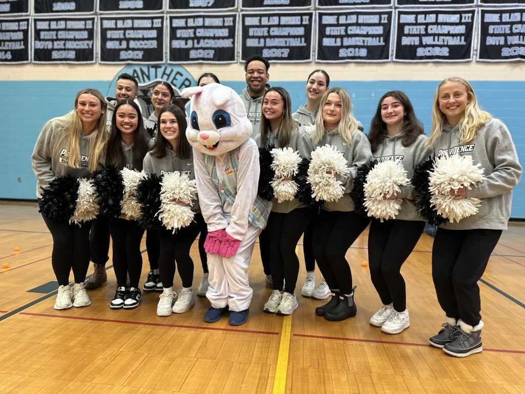 The Easter Bunny poses with several Providence College cheerleaders who are holding pom poms in front of them.
