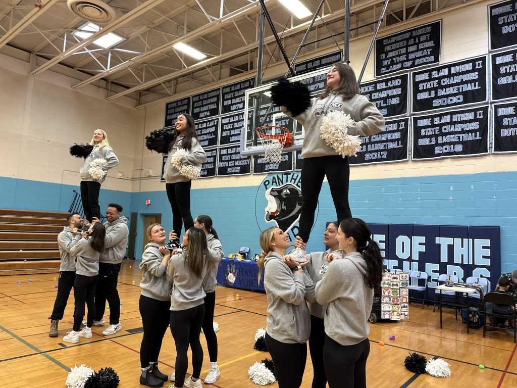 The Providence College Cheerleaders form a pyramid as they cheer on the crowd with pompoms in their hands.