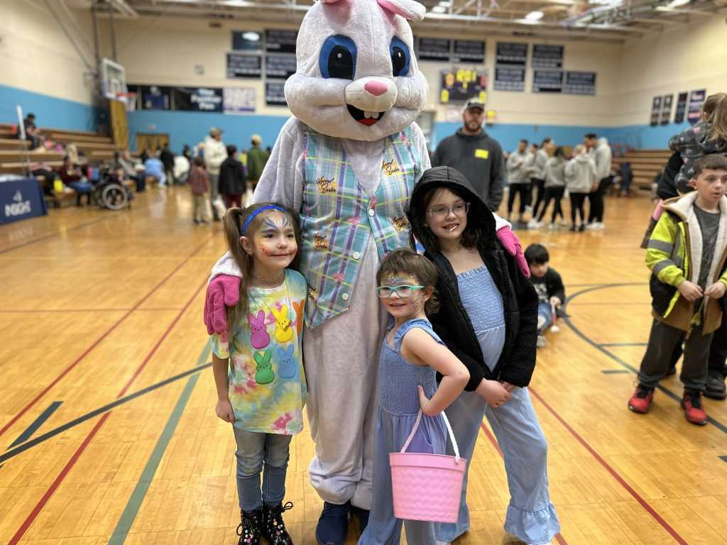 Three young girls pose for a picture with the Easter Bunny.