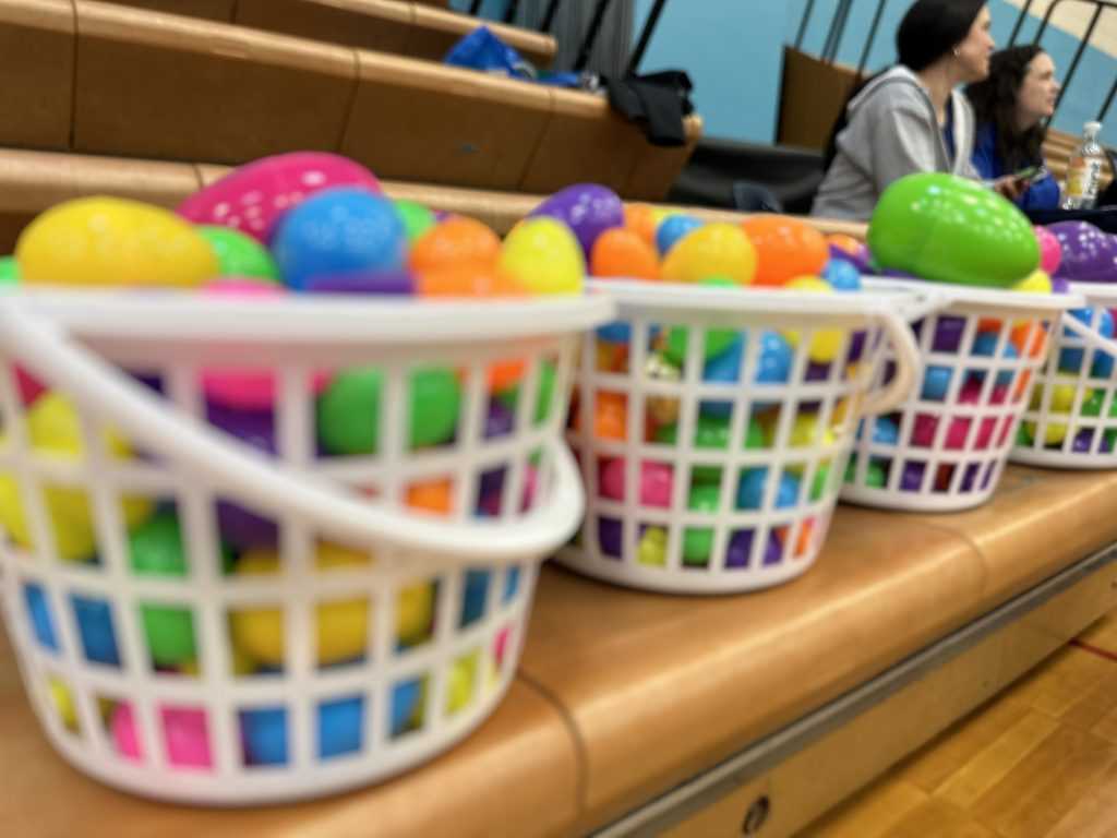 Four large white baskets filled with colorful plastic eggs.